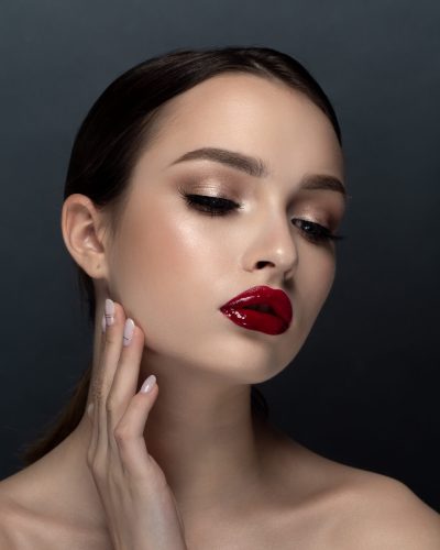 Portrait of young beautiful woman with evening make up touching her face. Makeup, luxury skincare and cosmetology concept